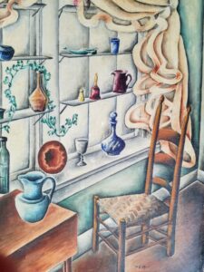 Wooden ciair with a woven seat faces a small table with a pitcher. The wall behind is contains pitchers, vases, a shoe, bell, salt shaker, plate, and a goblet.