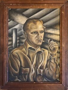 John Arnold, wearing a brown shirt, holds a pipe and looks to the side.